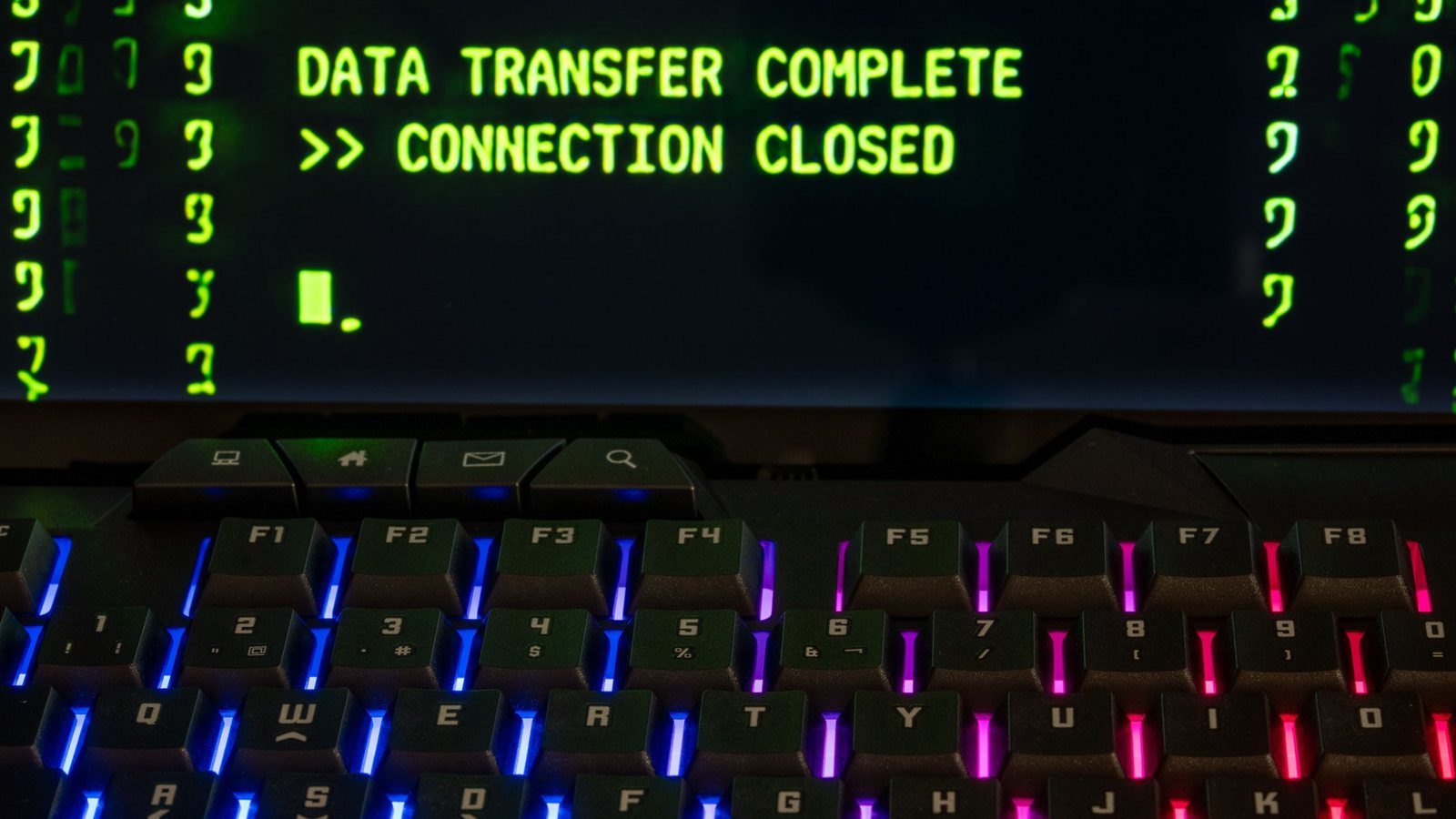 A screen reading "Data transfer complete, connection closed" above a backlit keyboard