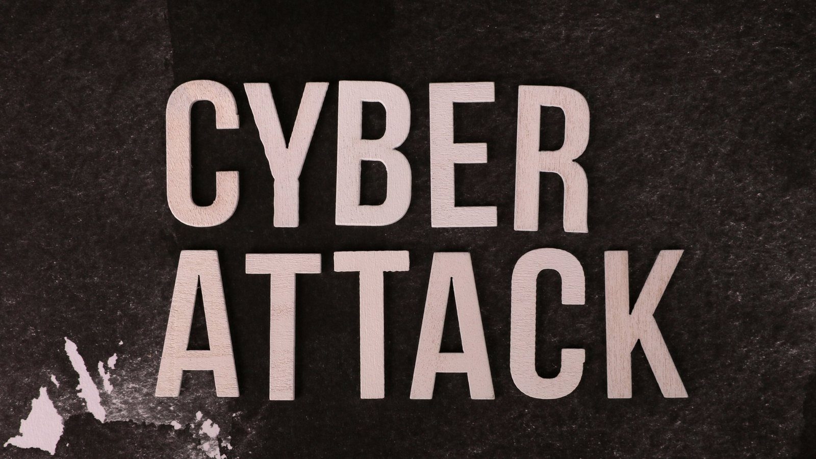 Wooden letters spelling "Cyber Attack" on dark textured paper